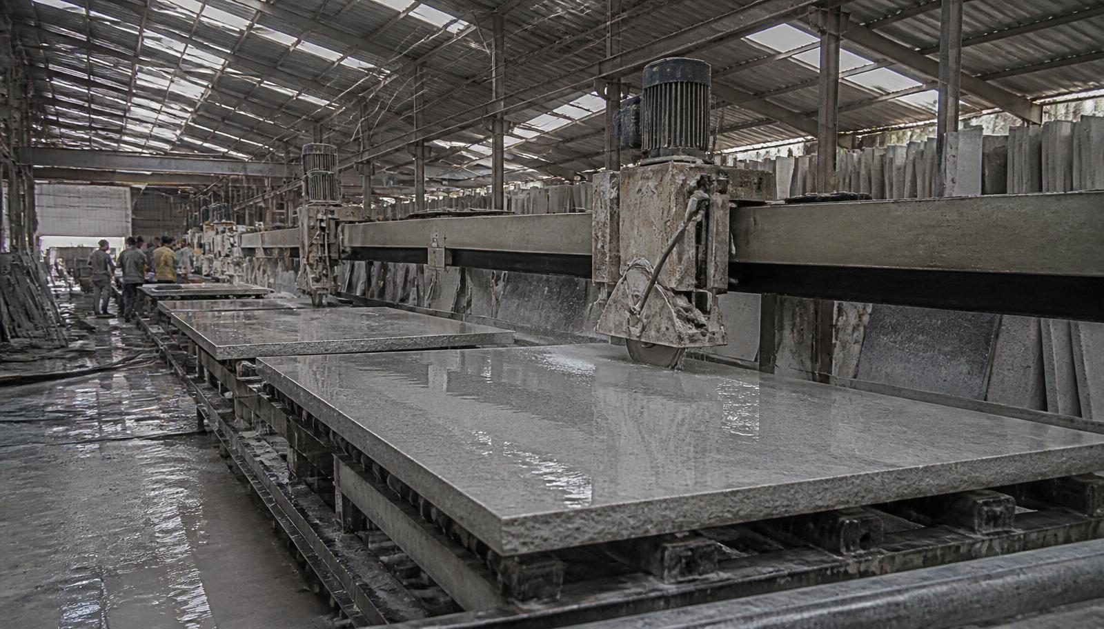 Gantry cutting and polishing lines running water over grey Shahabad limestone slabs at the polishing yard