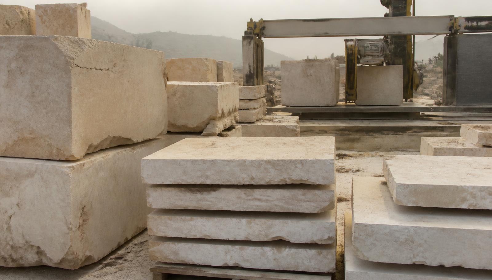 Sawn Shahabad limestone blocks and thick slabs stacked beside the gantry saw at the yard